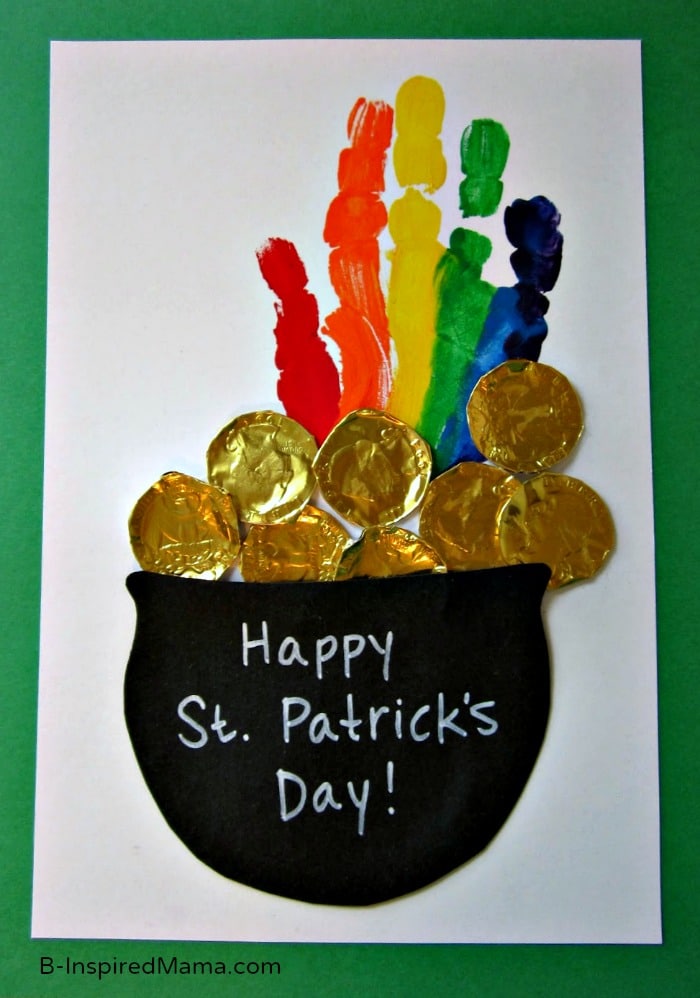 Leprechaun pot of gold made with a black felt cauldron, chocolate gold wrappers, and a handprint rainbow with the colors red, orange, yellow, green, and blue.
