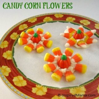 A photo of 3 cute Halloween treats made out of white chocolate melt, mellowcreme pumpkins, and candy corn arranged in the shape of flowers.