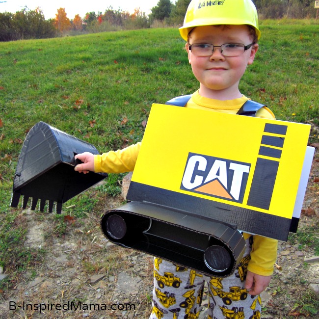 A young boy smiling and wearing a yellow and black homemade Caterpillar Construction Excavator costume for Halloween.