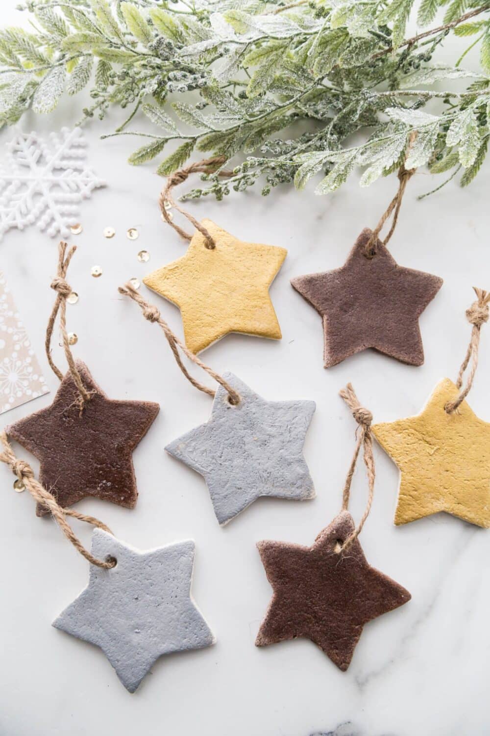 A photo of a group of homemade salt dough star ornaments painted in gold, silver, and brown, a fun ornament idea for preschoolers or kids of any age.
