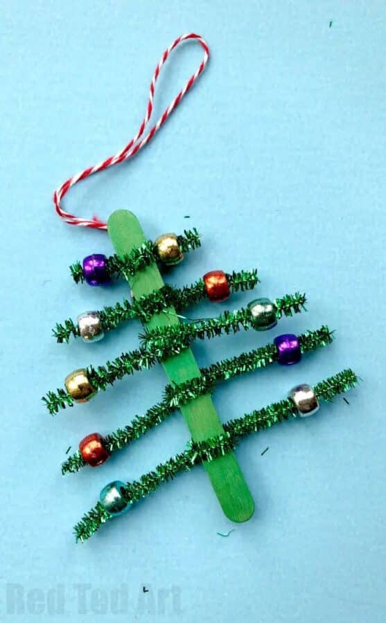 A photo of an easy ornament craft for preschool using green pipe cleaners twisted around a green craft stick to look like a little Christmas tree.