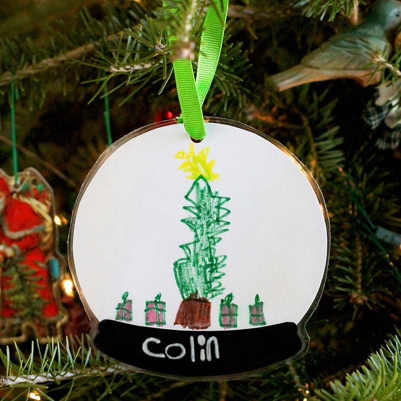 A paper snow globe ornament craft for preschoolers featuring a child's art inside the snow globe.