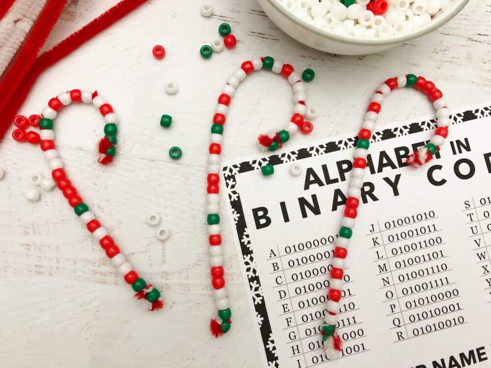 A photo of an educational ornament idea for preschoolers teaching them binary coding while making candy cane Christmas ornaments out of pipe cleaners and colorful beads.