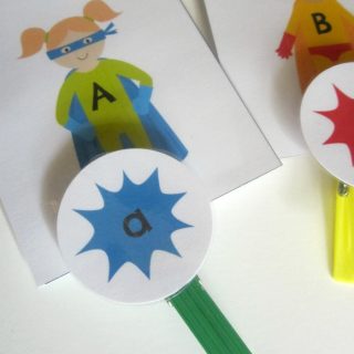 A photo of a free superhero upper and lowercase letters printable game made out of printed alphabet cards and colorful clothespins.