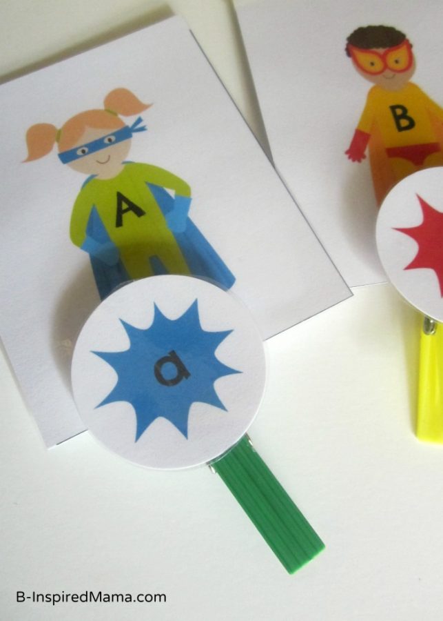 A photo of a free superhero upper and lowercase letters printable game made out of printed alphabet cards and colorful clothespins.