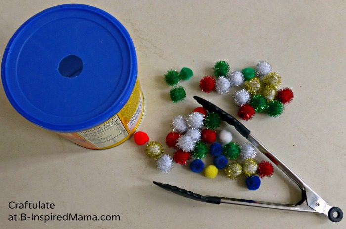 A photo of the supplies for a tongs and pom pom activity for toddlers.
