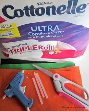 A collection of some of the supplies for making the "Pumpkin Chuckin'" game including rolls of toilet papers, orange and green felt, fabric scissors, a hot glue gun and glue sticks.