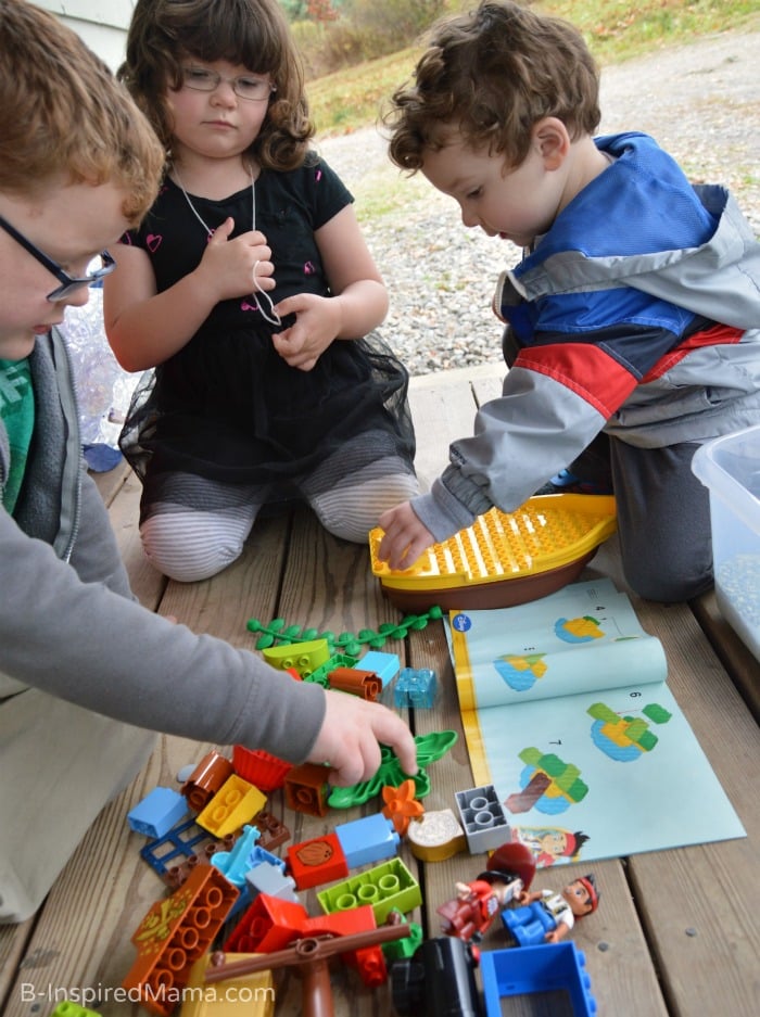 A photo of three children putting together a LEGO Duplo Pirate.