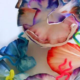 A photo of colorful craft flowers and butterflies made out of the colorful dyed coffee filters from a Marker Chromatography Experiment for kids.