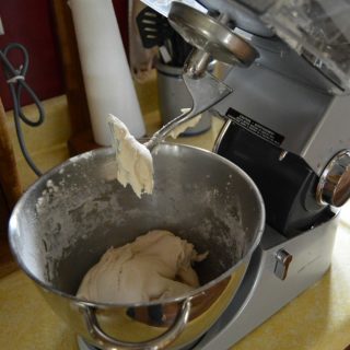 A photo of homemade play dough being made inside a kitchen stand mixer.