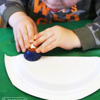 A photo of a young child punching holes while making a mobile craft.