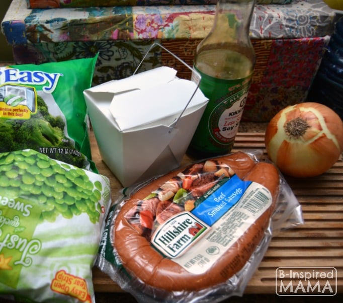 A photo of the ingredients for a Smoked Sausage and Rice Skillet Recipe, including a package of Hillshire Farm Smoked Sausage, frozen broccoli and peas, an onion, leftover white rice, and soy sauce.