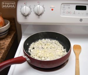 A photo of a frying pan on a stove with chopped onions in it, for a Smoked Sausage and Rice Skillet Recipe.