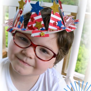 A photo of a young child wearing a patriotic paper plate crown 4th of July craft.