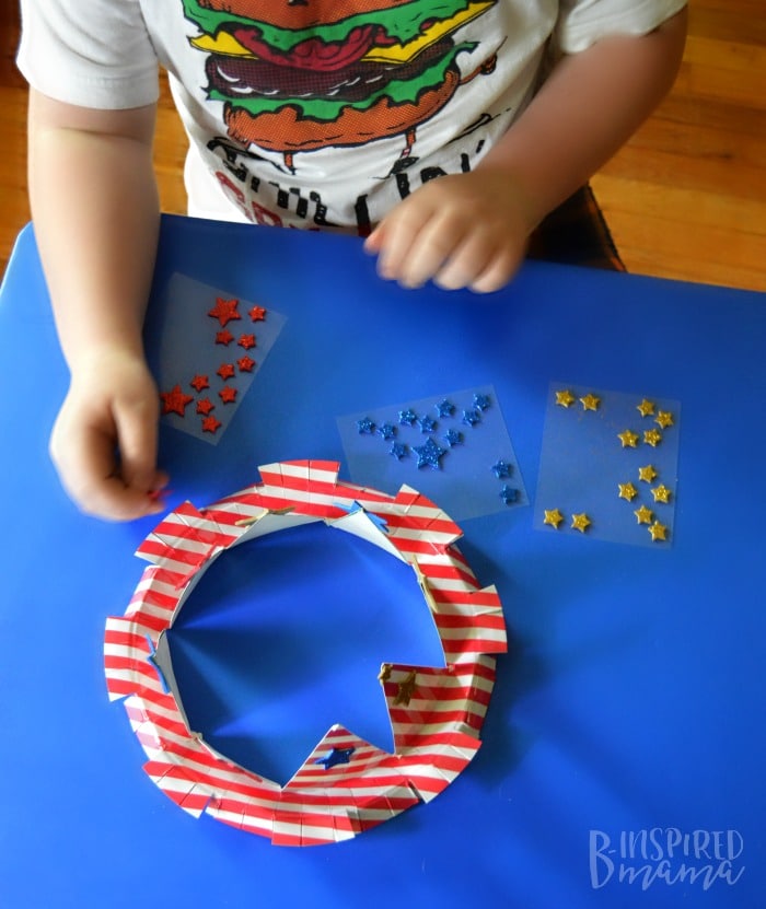 An Easy 4th of July Craft for Kids - A Stars and Stripes Crown - Sawyer adding the star stickers - at B-Inspired Mama
