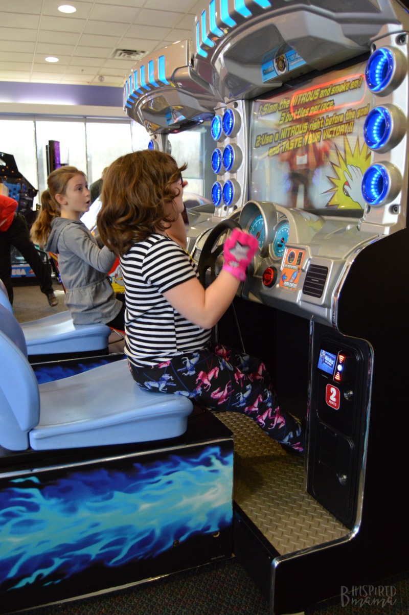 Priscilla and her friend loving the racing game at her Chuck E. Cheese's Birthday Party + Birthday Traditions for Kids - at B-Inspired Mama