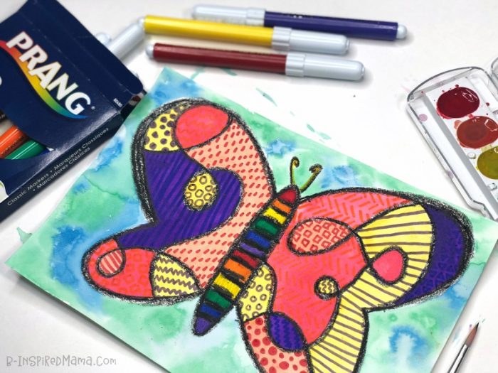 A photo of a colorful, pattern-filled watercolor butterfly painting for kids, along with some kids art supplies including Prang markers and watercolor paints.