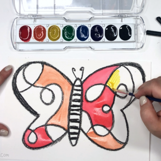 A photo of a hand painting the wings of a watercolor butterfly painting for kids.