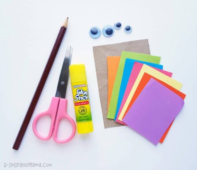 A photo of the materials and supplies for a kids shape turkey craft, including a pencil, a pair of scissors, a glue stick, construction paper, and googly eyes.