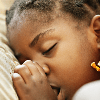 A photo of an African American child sleeping while sucking their thumb.