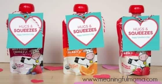 Three fruit pouch Valentines consisting of berry and applesauce pouch snacks with printable Valentine tags on them reading "Hugs and Squeezes." A great no-candy Valentine idea for kids of all ages.