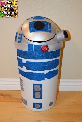A DIY Valentine box idea using a white plastic swing-lid garbage can decorated with silver paint, blue, black, and red paper, and cardboard tubes to look like R2-D2 from Star Wars.